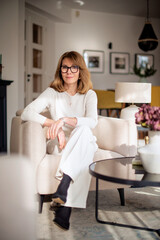 Portrait of a blond haired woman relaxing in an armchair at home