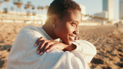 Close-up of  happy girl in light colored casual clothes sits on the beach