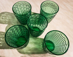 Five Green patterened Glasses and  reflections on white background , empty