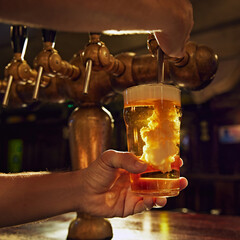 Close-up of male bartender hands pouring beer from tap into glass. Aesthetic of pub work and vintage luxurious settings. Concept of beer, brewery, pub, Oktoberfest, traditions