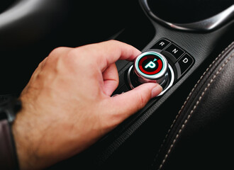 Driver hand turning a rotary gear shift dial on the dashboard of an EV car or electric vehicle , P...