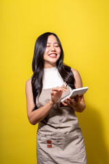 A woman wearing a white shirt and apron is smiling and holding a tablet