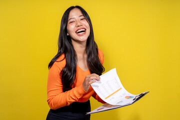 Fototapeta premium A woman in an orange shirt is holding a clipboard with a smile on her face