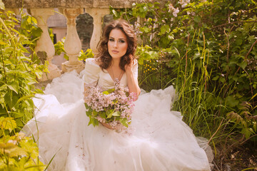 Portrait of beauty bride in white dress. The bride is holding a wedding bouquet of lilacs.