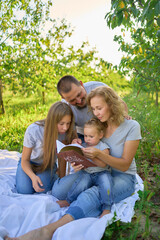 family reading the holy bible on a picnic in the garden © Victoria Antre