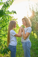 Obraz premium mother and teenage girls with long blond hair spend time together in the sunlit park