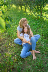 Fototapeta premium mother and teenage girls with long blond hair spend time together in the sunlit park