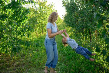  mother spins the toddler in the air holding his arms and legs