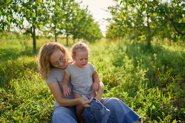 Fototapeta premium mother dresses toddler who screams, hates getting dressed