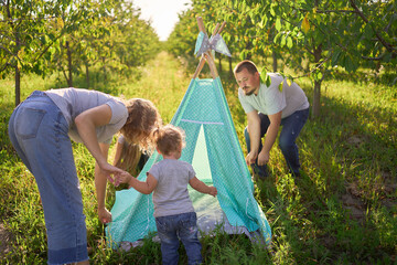 family with toddler playing in wigwam in garden © Victoria Antre