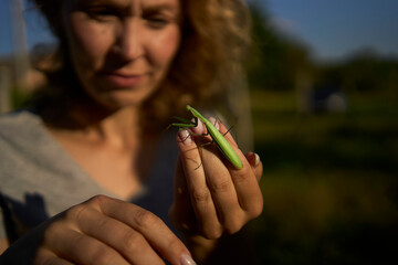 a woman holds a large grasshopper on her hand