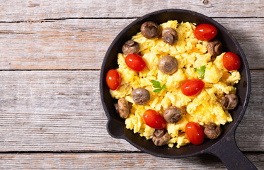 Healthy vegetarian breakfast . Scrambled eggs in pan with cherry tomatoes and parsley