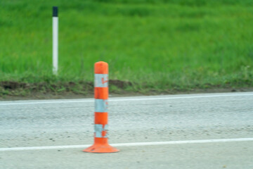 A row of orange and white traffic cones are lined up on a road. The cones are spaced out and are not in use.