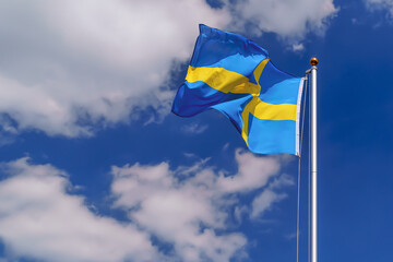 Sweden flag flying on a flagpole, strong wind