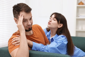 Woman trying to kiss embarrassed man at home