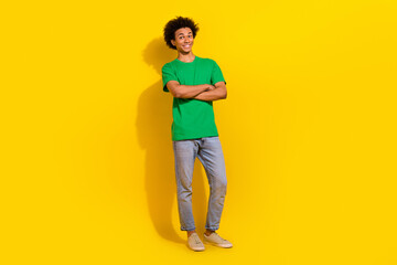 Fototapeta premium Full length photo of attractive funny guy wear green t-shirt arms crossed emtpy space isolated yellow color background