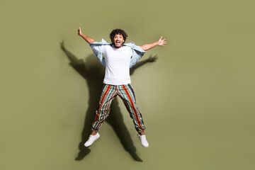 Full size photo of handsome young guy jump stretch hands legs wear trendy jeans outfit isolated on...