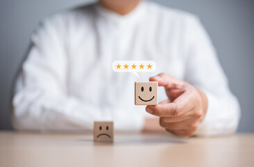 Customer service review. Client holds a smiley happy face on wooden cube with text review symbol....