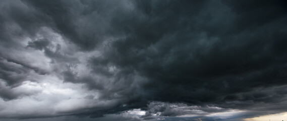 Obraz premium Bad or moody weather sky and environment. carbon dioxide emissions, greenhouse effect, global warming, climate change. The dark sky with heavy clouds converging and a violent storm before the rain.