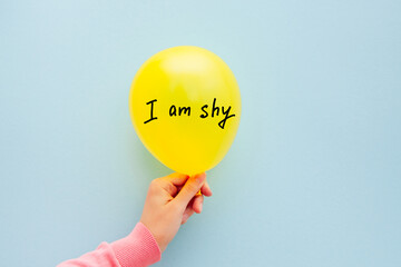 I am shy - woman hand is holding air balloon with text on light blue background, introvert type and...