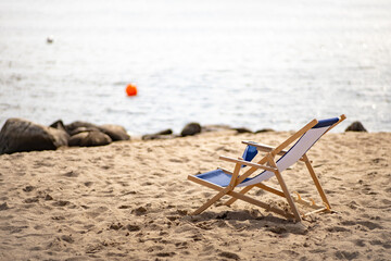 Liegestuhl am Strand mit Boje auf dem Wasser