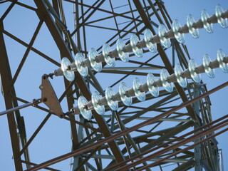 close-up photo of  disc insulators mounted on high-voltage power lines with blue sky visible in the...