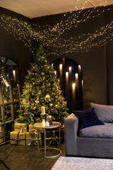 Christmas interior with a beautiful Christmas tree, sofa, light bulbs and dark background.