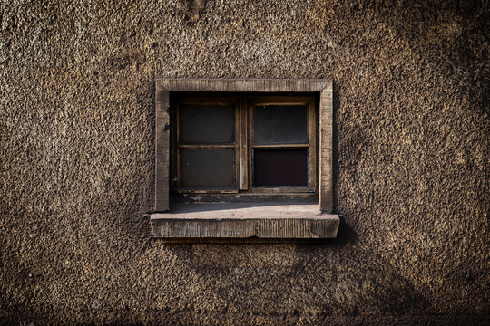 Altes Fenster in grob verputzter Wand mit viel Dreck und Schmutz