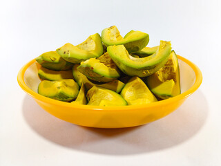 Thick Slices of Avocado Stacked Together on a Plate with Yellow Accent Against a White Background: Fresh and Creamy Avocado Presentation in a Bright, Minimalist Setting
