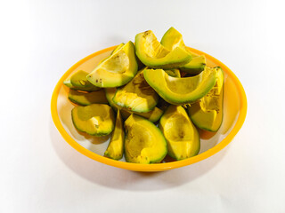 Thick Slices of Avocado Stacked Together on a Plate with Yellow Accent Against a White Background: Fresh and Creamy Avocado Presentation in a Bright, Minimalist Setting