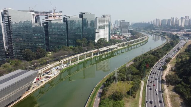 Vis&atilde;o a&eacute;rea de pr&eacute;dios comerciais a beira do rio tiet&ecirc; com o fluxo de ve&iacute;culos no tr&acirc;nsito da marginal pinheiros na cidade de s&atilde;o paulo, sp, brasil captada por um drone em 2024