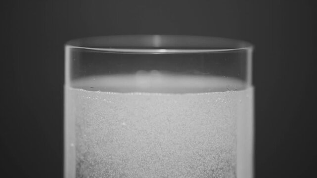 Rising air bubbles in water, effervescent powder dissolving, dark black background

