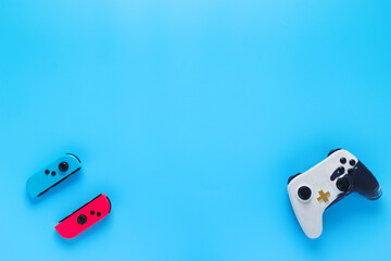 Two video game controllers from different consoles on a minimalist blue background, concept of visual resource for marketing presentation in video games