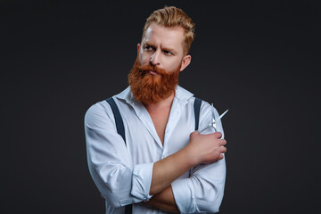 Barber using scissors isolated on black. Haircut from a hairstylist at a barbershop. Bearded Caucasian man hairdresser in hair salon. Hairstylist working in a hair salon. Premium barbershop