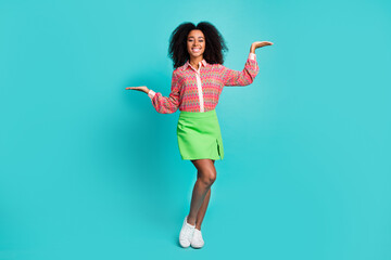 Full length photo of adorable lovely girl wear print shirt comparing two arms empty space isolated...