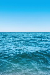 Fototapeta premium A serene view of calm ocean water under a clear blue sky, perfect for conveying tranquility and relaxation.