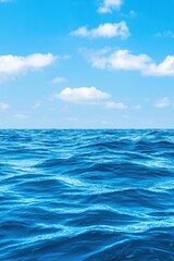Fototapeta premium Tranquil ocean view featuring vibrant blue water and fluffy clouds against a clear sky, ideal for relaxation and nature themes.