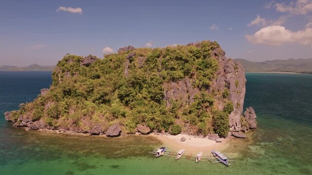 Aerial panoramic view of tropical paradise rocky island surrounded by crystal blue sea, sail boats and tourists. Travel video of Bukal island El Nido Philippines, untouched nature on sunny summer day
