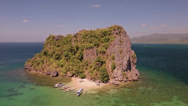 Aerial panoramic view of tropical paradise rocky island surrounded by crystal blue sea, sail boats and tourists. Travel video of Bukal island El Nido Philippines, untouched nature on sunny summer day