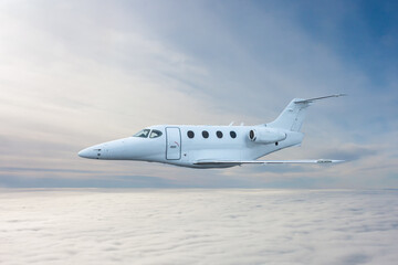 White executive airplane flying in the air above the clouds