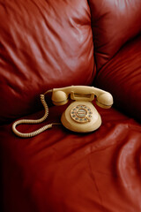 Classic white rotary phone placed on a bold red leather couch, evoking retro vibes