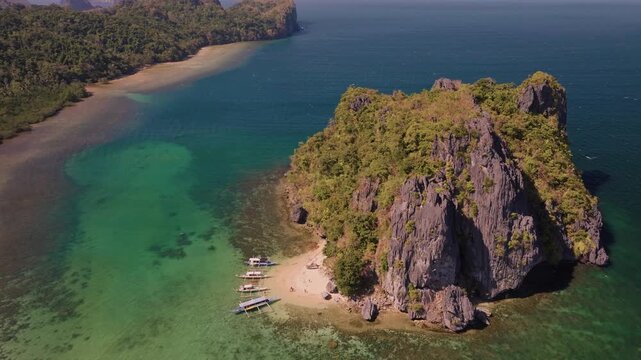 Establishing aerial view of tropical paradise exotic island surrounded by crystal blue sea and sail boats. Travel video of Bukal island El Nido Philippines, untouched nature on sunny summer day