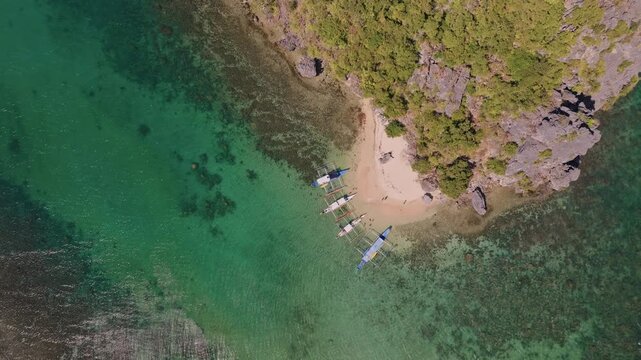 Establishing aerial view of tropical paradise exotic island surrounded by crystal blue sea and sail boats. Travel video of Bukal island El Nido Philippines, untouched nature on sunny summer day