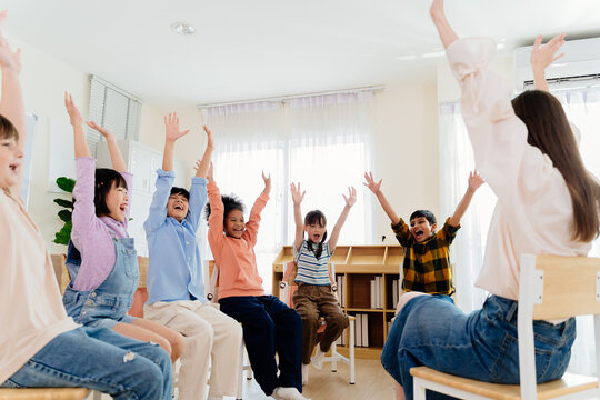 Excited primary school kids from various backgrounds express happiness together. Cheerful classroom scene captures essence of modern education, highlighting unity and active participation