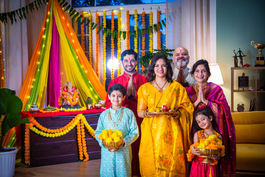 Indian Asian family performing Ganesh Puja at home in traditional attire, celebrating with devotion