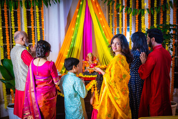 Indian Asian family performing Ganesh Puja at home in traditional attire, celebrating with devotion
