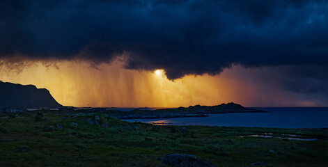 Dark storm clouds clearing at sunset create drama over the mountain and the rocky shore.  Lofoten islands, Northern Norway. © Iraj Nouri