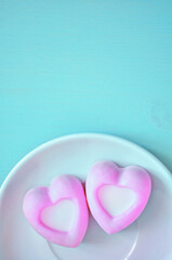 Souffle dessert, french souffle cakes. Two heart-shaped pink souffle cakes lying on the white porcelain plate on the turquoise wooden table. Selective soft focus on the cake