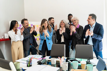 Diverse team celebrating project completion: multigenerational professionals in vibrant office meeting