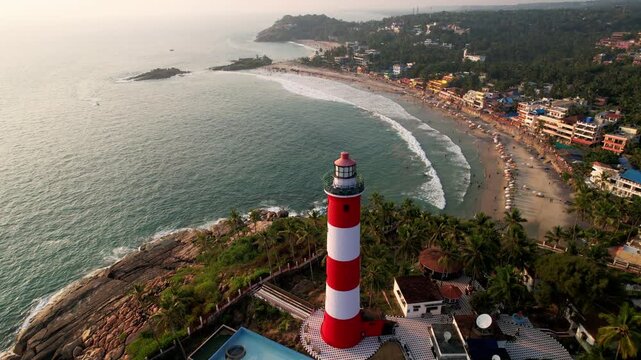 Lighthouse tower on a rocky coastline at sunset, Aerial View. Kovalam Beach whith Lighthouse in India, Kerala